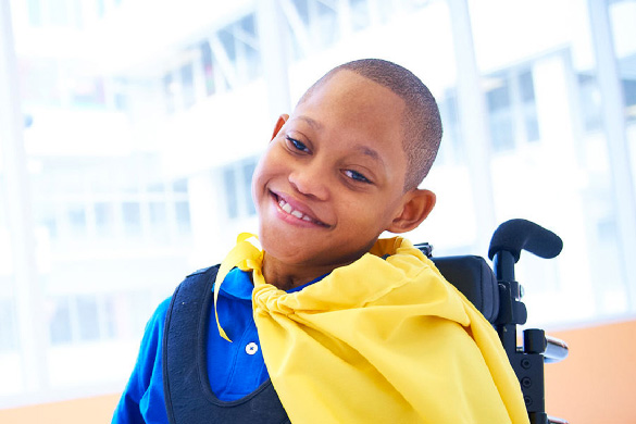 kid in a wheelchair wearing a yellow cape